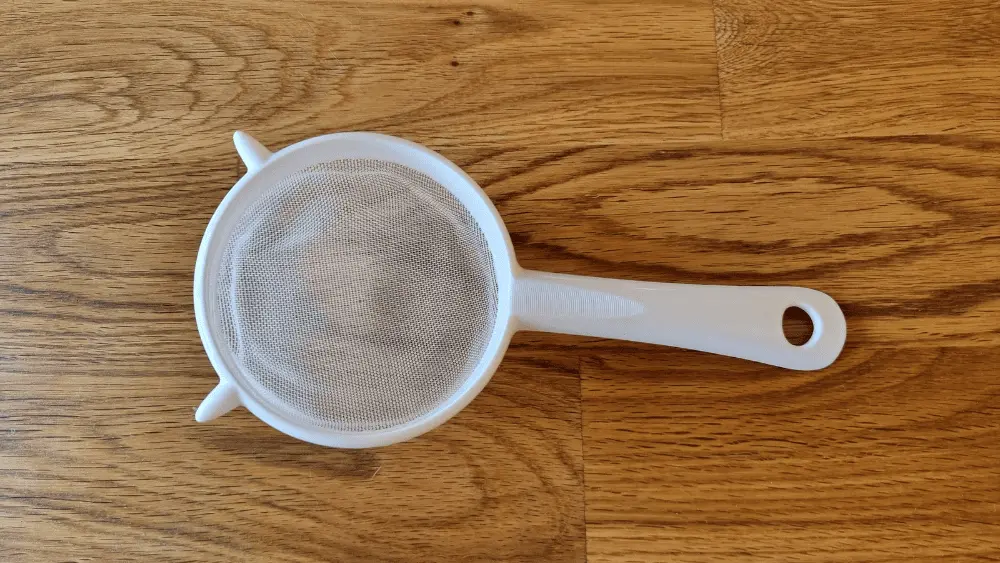 kleines weißer Sieb auf einem Holztisch